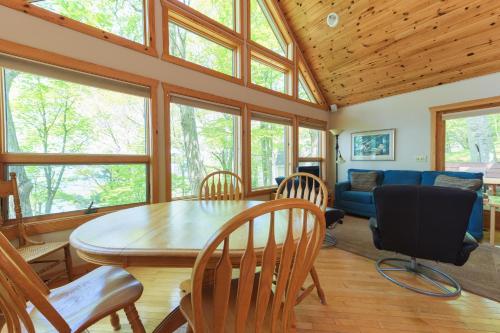 a dining room with a table and chairs and a couch at Gebhard Chalet - Charming, private, beachfront chalet nestled in a wooded dune on Lake Michigan in Coloma