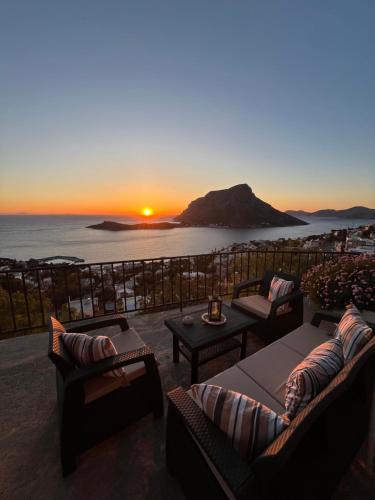a sunset over the ocean with couches and a table at Elsa's house in Kalymnos