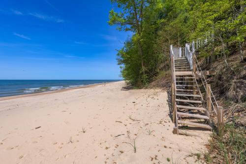 a staircase leading up to a beach with the ocean at Gebhard Chalet - Charming, private, beachfront chalet nestled in a wooded dune on Lake Michigan in Coloma