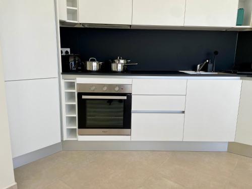 a kitchen with white cabinets and a stove top oven at Bugibba Square Seafront LUX Apartments by Holi in St Paul's Bay