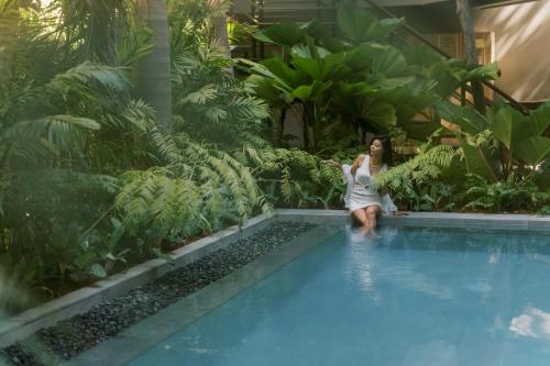 uma mulher sentada à beira de uma piscina em Piece Lio Resort from Japan em El Nido
