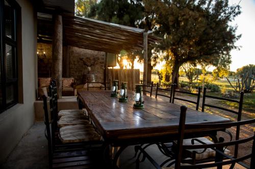 a wooden table on a porch with chairs around it at Grootvallei Guest Farm - Main lodge in Boshof