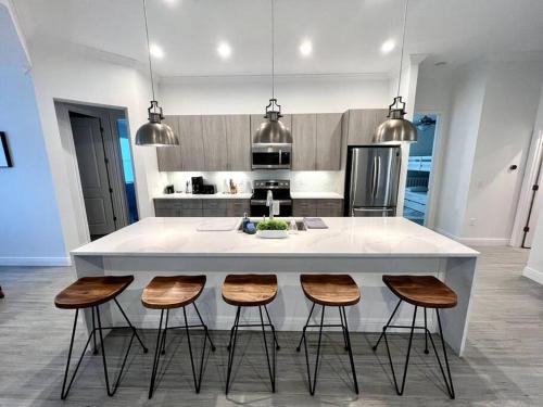 una cocina con una isla blanca con 4 taburetes en Smart Home Sarasota Family Getaway, en Osprey