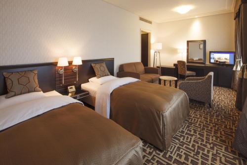 千葉市にあるオークラ千葉ホテルのベッド2台とテレビが備わるホテルルームです。