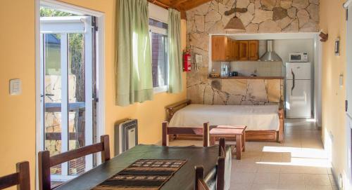 Habitación con cama, mesa y cocina. en Cabañas Mellmell en Mar de las Pampas