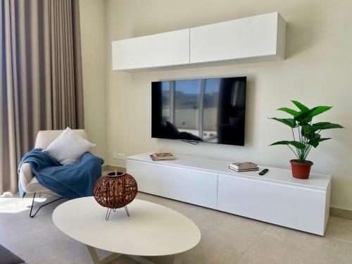 a living room with a tv on the wall at Bugibba Square Seafront LUX Apartments by Holi in St Paul's Bay