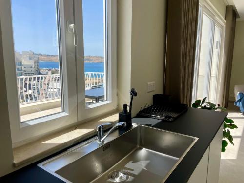 a kitchen with a sink and a large window at Bugibba Square Seafront LUX Apartments by Holi in St Paul's Bay