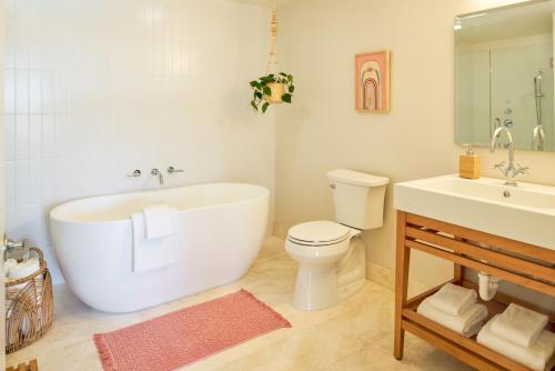 a bathroom with a tub and a toilet and a sink at The Saguaro Palm Springs in Palm Springs