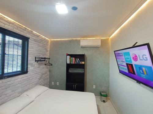 a bedroom with a bed and a flat screen tv at Praia do Bessa, Caribessa - Quarto Privativo - Conforto, Paz e Sossego, excelente para descansar, trabalhar ou estudar in João Pessoa