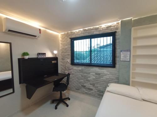 a living room with a desk and a window at Praia do Bessa, Caribessa - Quarto Privativo - Conforto, Paz e Sossego, excelente para descansar, trabalhar ou estudar in João Pessoa