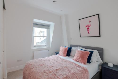 een slaapkamer met een bed met roze en blauwe kussens bij Soul in the City - Fitzrovia - By frankie Says in Londen