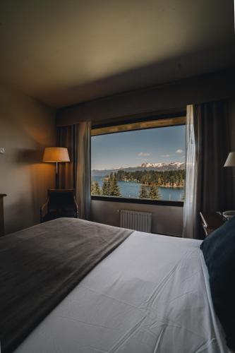a bedroom with a large bed and a large window at Marinas Alto Manzano in Villa La Angostura