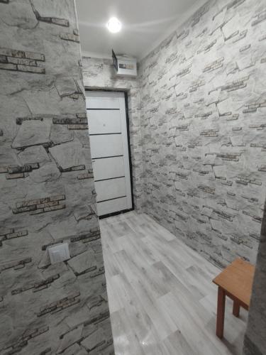 Habitación con pared de piedra y puerta en Квартира, en Baljash