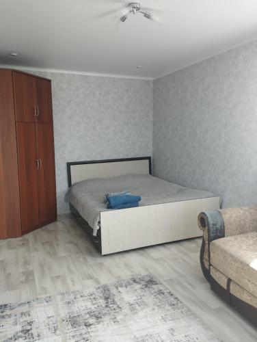 1 dormitorio con 1 cama y armario de madera en Квартира, en Baljash