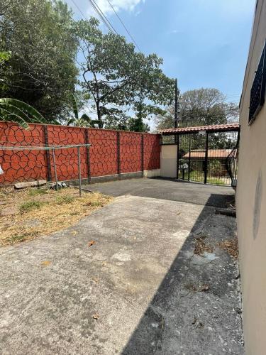 an empty driveway in front of a red fence at A 5 minutos del aeropuerto in Alajuela City