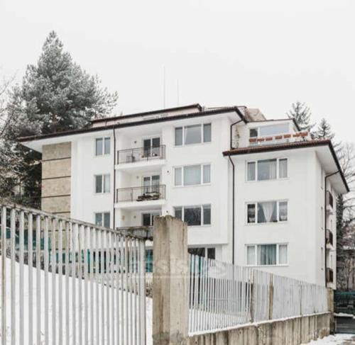 Ein weißes Gebäude mit einem Zaun davor. in der Unterkunft Apartment in Boyana in Sofia
