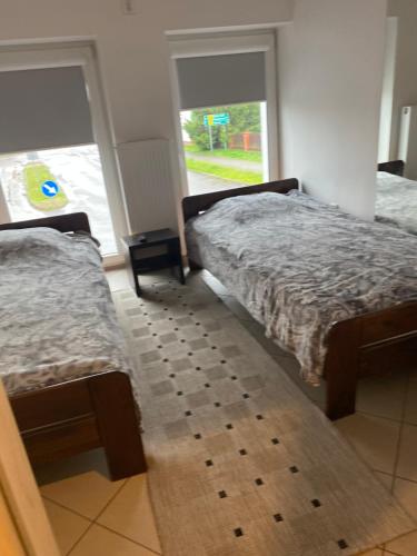 2 Betten in einem Zimmer mit 2 Fenstern in der Unterkunft Tanie Nocowanie in Parczew
