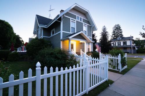 a white picket fence in front of a house at For Pete's Sake - private pickleball court & 2 blocks to beach! in South Haven