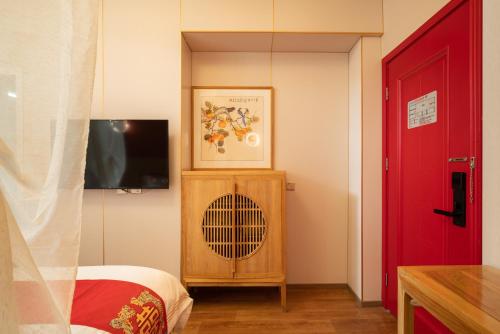a room with a red door and a bedroom with a fan at Rong Hotel - Beijing Nanluoguxiang Branch in Beijing