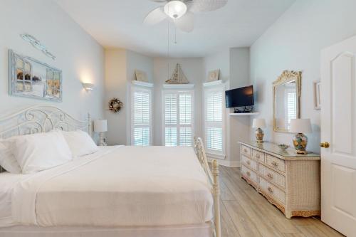 a white bedroom with a bed and a tv at Cotton Candy in Destin