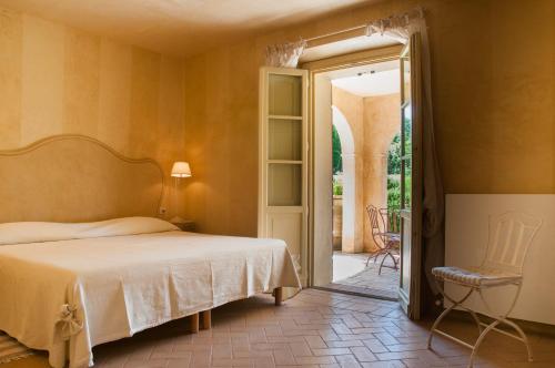 1 dormitorio con cama, silla y puerta abierta en Tenuta del Fontino, en La Pesta