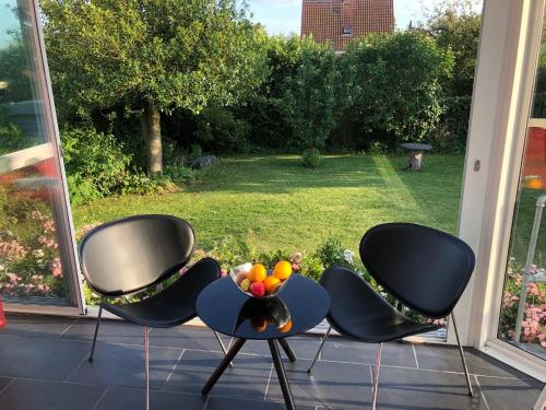 3 chaises et un bol de fruits sur une terrasse couverte dans l'établissement Beautiful hygge apartment Dk, à Søborg