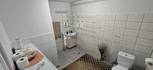 a white tiled bathroom with a toilet and a sink at Amya - Centrul istoric in Braşov