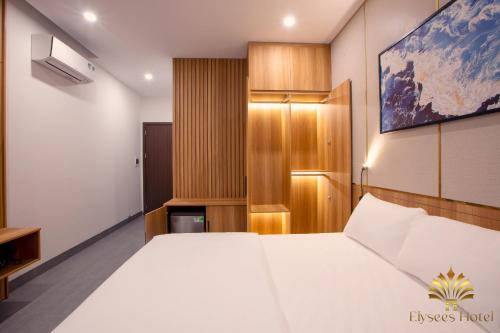 a bedroom with a large white bed and a cabinet at Elysees Sam Son Beach Hotel in Thanh Hóa