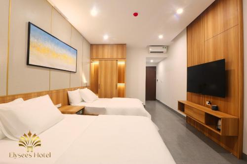 a hotel room with two beds and a flat screen tv at Elysees Sam Son Beach Hotel in Thanh Hóa