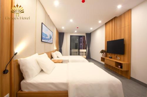a hotel room with two beds and a flat screen tv at Elysees Sam Son Beach Hotel in Thanh Hóa