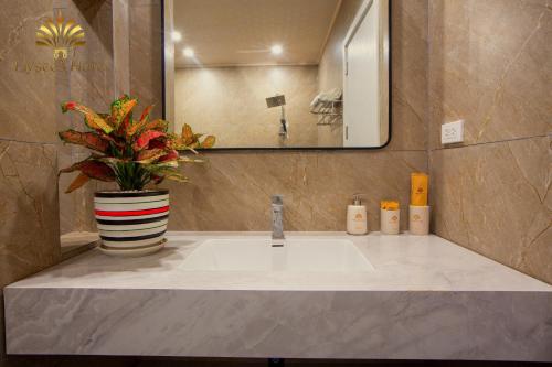 a bathroom with a sink and a vase with a plant at Elysees Sam Son Beach Hotel in Thanh Hóa
