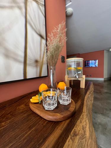 a table with two glasses and a vase with oranges at Pousada Cerrado in Goiânia