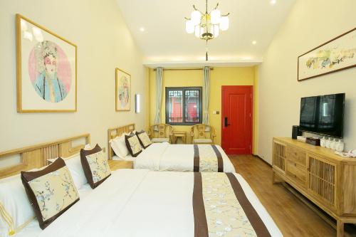 a bedroom with two beds and a flat screen tv at Rong Hotel - Beijing Nanluoguxiang Branch in Beijing
