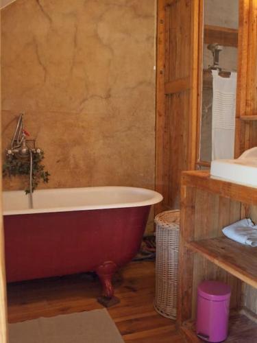 La salle de bains est pourvue d'une baignoire rouge et d'un lavabo. dans l'établissement La Maison Cabane, à Saint-Martin-le-Hébert
