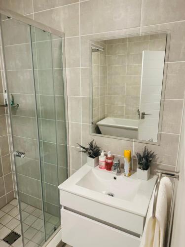 a bathroom with a sink and a shower with a mirror at Napo Luxury stay in Pretoria