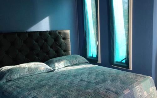 a bedroom with a bed and two windows at Cabañas con Tinaja 10 personas in Quillón
