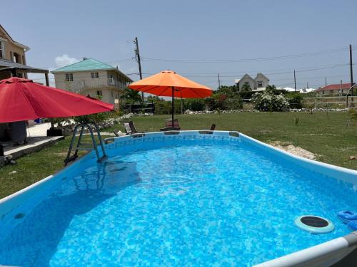 - une piscine avec un parasol rouge et un parasol rouge dans l'établissement ABBE Garden Hideaway, à Saint Philip