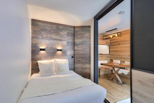 une chambre avec un lit blanc et un mur en bois dans l'établissement L'Aiguille - maeva Home - Appartement 2 pièces 4 personnes Exclusive MAE-1386, à Chamonix-Mont-Blanc
