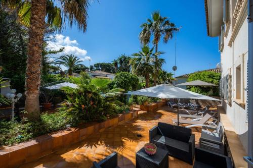 a patio with chairs and umbrellas and palm trees at Villa Pedro strandnah ruhig zentral in Can Pastilla