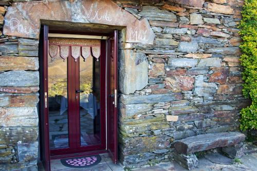 a stone building with a red door and a stone wall at Casa Margou in São Pedro do Sul