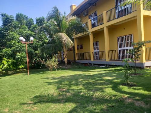 a yellow building with a palm tree in the yard at Moradia Turística MJ ROOMS CITY in São Tomé