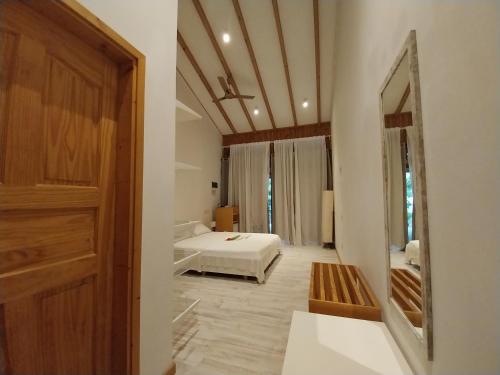 1 dormitorio con cama y espejo grande en Origami Inn Himandhoo, en Himandhoo 