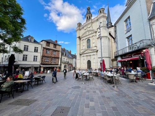 um grupo de pessoas sentadas em mesas em uma rua da cidade em Appartement cosy hypercentre Place St Pierre em Saumur