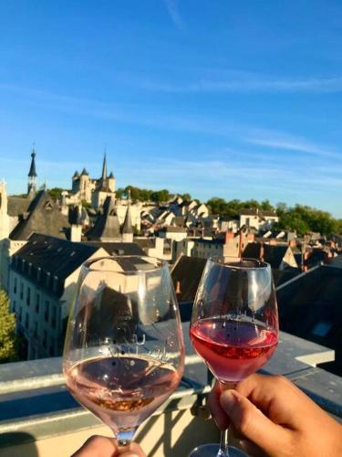une personne tenant un verre de vin sur un balcon dans l'établissement Appartement cosy hypercentre Place St Pierre, à Saumur