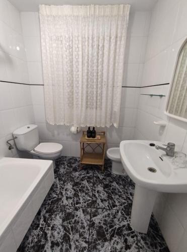 a white bathroom with a sink and a toilet and a tub at Apartamentos Faxilda in Sanxenxo