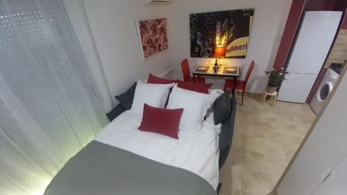 a bedroom with a white bed with red pillows at El estudio de las mariposas,sofa cama , cocina y baño in Partida de La Cañada