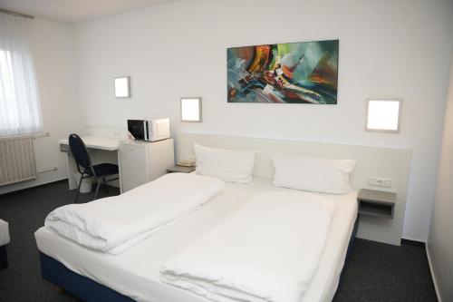 een slaapkamer met een bed met witte lakens en een bureau bij Weber Residenz in Mannheim