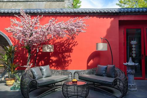 a patio with two chairs and a red wall at Rong Hotel - Beijing Nanluoguxiang Branch in Beijing
