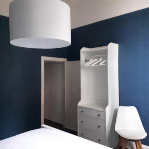 a bedroom with a white bed and a blue wall at Het Koetshuis, op 50m van zee, voor 5 personen, centrum Westende BAD, alle comfort in Middelkerke