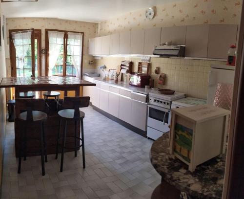 une cuisine avec des armoires blanches et une table et des chaises dans l'établissement Les Hêtres Inséparables aux portes du DDay, à Bernesq